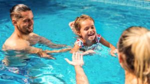 Niño juega con sus padres en la piscina